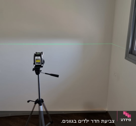 מכשיר לייזר על חצובה מכוון לקיר לבן